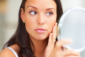 Woman looking in mirror at face 640X427 jpeg